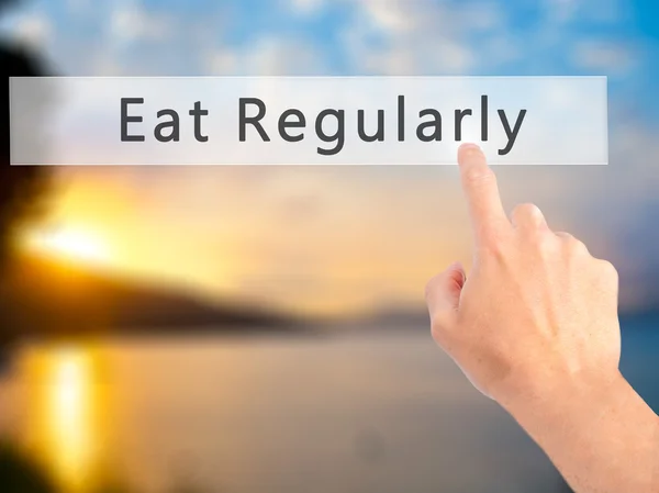 Eet regelmatig - Hand indrukken van een knop op de onscherpe achtergrond con — Stockfoto