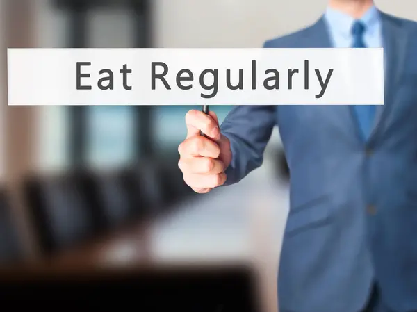 Jedz regularnie-biznesmen ręcznie znak gospodarstwa — Zdjęcie stockowe