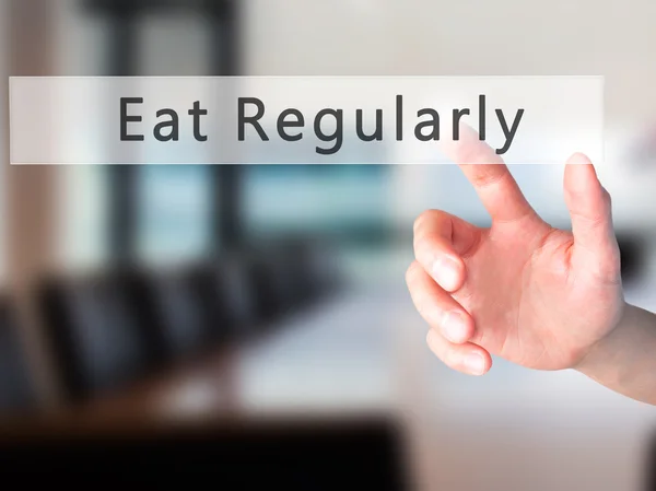 Mangiare regolarmente - Mano premendo un pulsante su sfondo sfocato con — Foto Stock