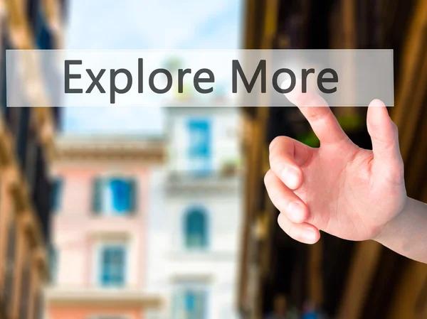 Explore More - Hand pressing a button on blurred background conc — Stock Photo, Image