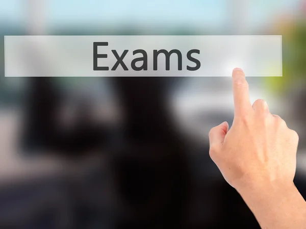 Exams - Hand pressing a button on blurred background concept on — Stock Photo, Image