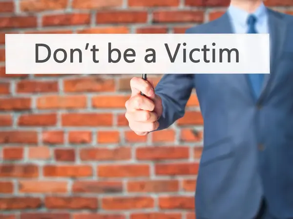 Don 't be a Victim - Businessman hand holding sign — стоковое фото