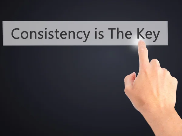 Consistency is The Key - Hand pressing a button on blurred backg — Stock Photo, Image