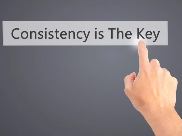 Consistency is The Key - Hand pressing a button on blurred backg — Stock Photo, Image