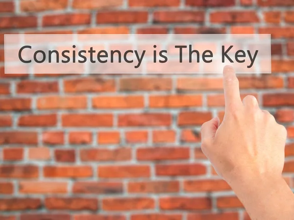 Consistency is The Key - Hand pressing a button on blurred backg — Stock Photo, Image