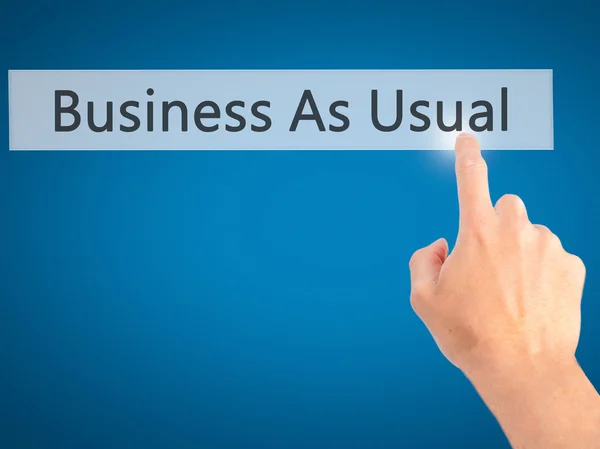 Business As Usual - Hand pressing a button on blurred background — Stock Photo, Image