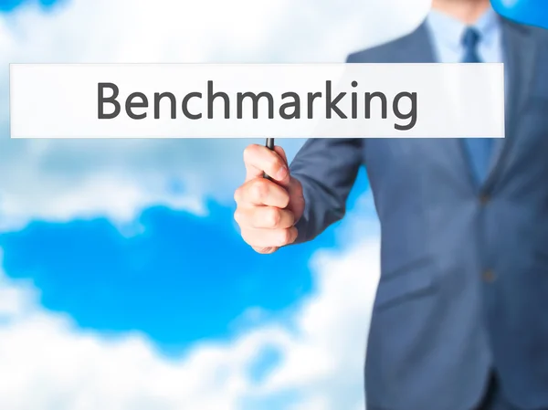 Benchmarking-affärsman hand innehav Sign — Stockfoto