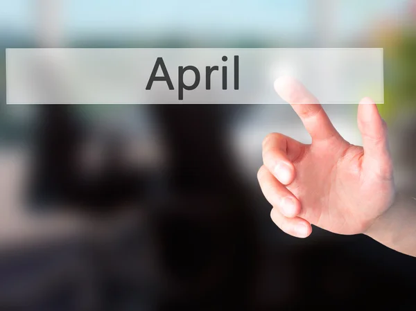 April - Hand indrukken van een knop op onscherpe achtergrond concept op — Stockfoto