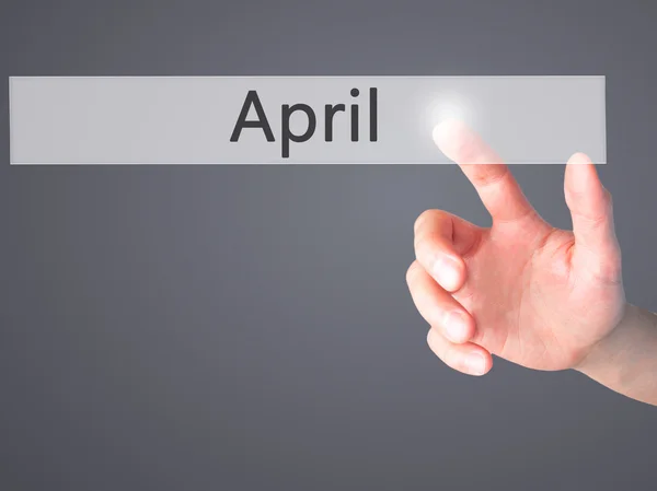 Április - kéz egy elmosódott háttér koncepció gomb lenyomásával — Stock Fotó