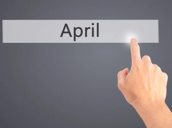 April - Hand indrukken van een knop op onscherpe achtergrond concept op — Stockfoto