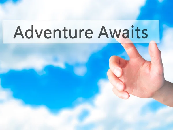 Adventure Awaits - Hand trycka på en knapp på suddig bakgrund — Stockfoto