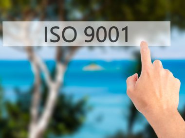 Iso 9001 - Bulanık arka plan konseptinde düğmeye basarak el 