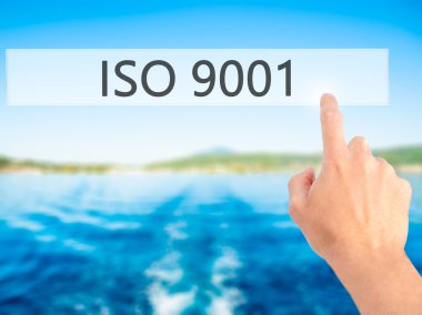 Iso 9001 - Bulanık arka plan konseptinde düğmeye basarak el 