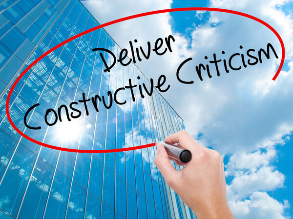 Man Hand writing Deliver Constructive Criticism with black marke