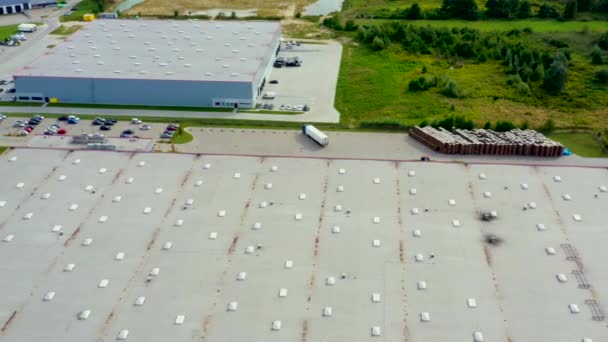 Luchtfoto na opname van opleggertrucks die langs een magazijn rijden op de parkeerplaats in het logistieke park met laadnaaf. — Stockvideo