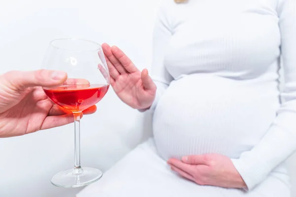 No alcohol during pregnancy. Young pregnant woman refuses to drink wine, making stop gesture to glass, free space