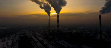 Elektrik santrali güneş doğarken şehrin üzerinde görüldü. Çevre kirliliği. Fabrika borusu hava kirletiyor. Panorama günbatımı. Sigara içilen borular Hava görüntüsü,