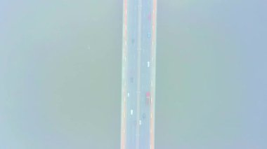 Hava aracı görüntüsü. Güneşli bir sabahta köprü. Havada sonbahar sisi var, arabalar köprüden geçiyor. Bulutlu bir gün.