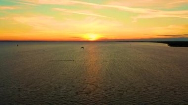 Hava görüntüsü. Güzel bulutların arkasında mavi denizde sörf yapan uçurtma. Gün batımı