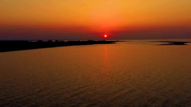 Drone 'un deniz üzerinde güneş batışı görüntüsü. Plajda turuncu renkli gün doğumu. Deniz dramatik denizinde gün batımı.