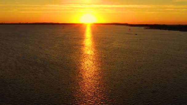 Lucht uitzicht, Kitesurfers zwemmen met hoge snelheid in de open zee bij zonsondergang. Drone schoot op drie atleten op planken die boven het wateroppervlak zweven. Polen Hel — Stockvideo