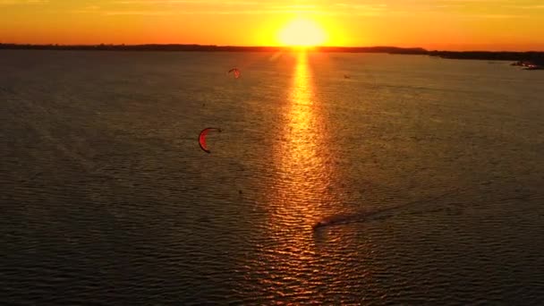 Vista aérea, Kitesurfers nadar em alta velocidade no mar aberto ao pôr do sol. Drone atirou em três atletas em tábuas flutuando acima da superfície da água. Polónia Hel — Vídeo de Stock