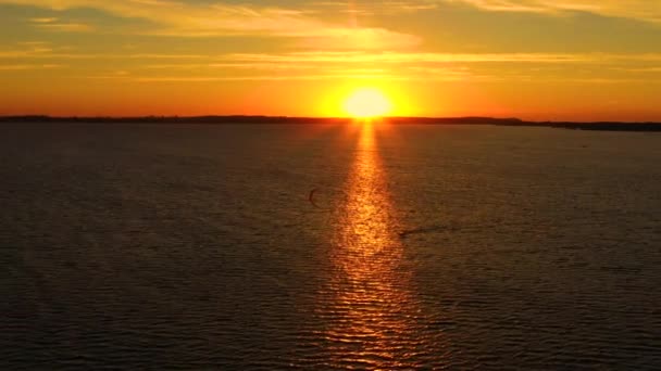 Lucht uitzicht, Kitesurfers zwemmen met hoge snelheid in de open zee bij zonsondergang. Drone schoot op drie atleten op planken die boven het wateroppervlak zweven. Polen Hel — Stockvideo