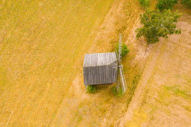 Eski ahşap değirmen bıçaklarını kapatın. Batan güneşin parlak gökyüzü. Arka planda küçük bir kavşak var. Havadan