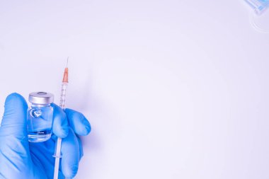 Beyaz zemin üzerinde aşı yapmadan önce şırıngayı tutan doktor ya da hemşirenin eldivenli eli. Covid19, Coronavirus Konsepti. Sifon atışı