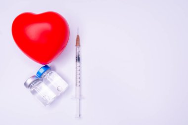 Tıbbi eldivendeki bir el, virüsün tüm dünyaya yayılmasını önlemek için icat edilen covid-19 aşısını içeren bir ampul taşıyor. Beyaz arka planda kırmızı kalpli bir maske