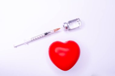 Tıbbi eldivendeki bir el, virüsün tüm dünyaya yayılmasını önlemek için icat edilen covid-19 aşısını içeren bir ampul taşıyor. Beyaz arka planda kırmızı kalpli bir maske