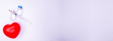 Tıbbi eldivendeki bir el, virüsün tüm dünyaya yayılmasını önlemek için icat edilen covid-19 aşısını içeren bir ampul taşıyor. Beyaz arkaplandaki kırmızı kalpli maske Boşluğu Kopyala