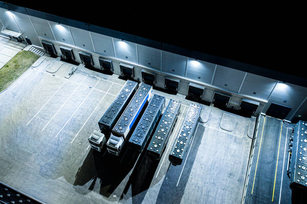 Aerial view of the trucks unloading at the logistic center. Night view.Trucks unloading at the logistic center. Drone photography.