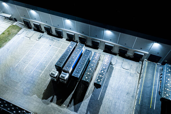 Aerial view of the trucks unloading at the logistic center. Night view.Trucks unloading at the logistic center. Drone photography.