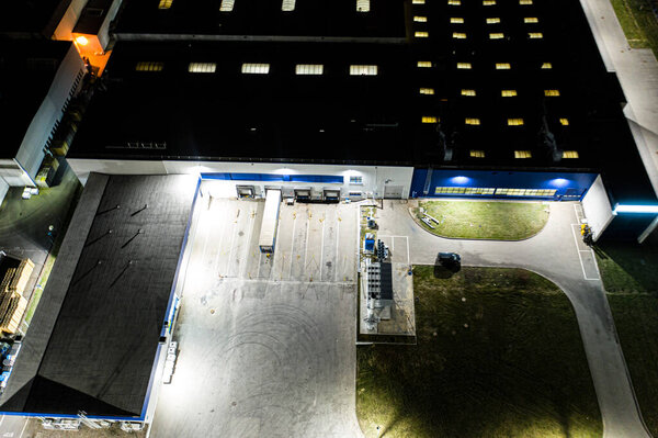 Aerial view of the trucks unloading at the logistic center. Night view.Trucks unloading at the logistic center. Drone photography.