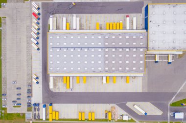 Malzeme deposunun havadan görüntüsü. Sanayi bölgesindeki lojistik merkezi yukarıdan. Lojistik merkezde yüklenen kamyonların hava görüntüsü. İnsansız hava aracından görüntüle.