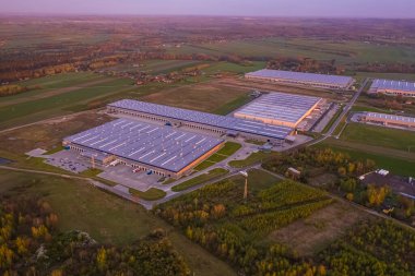 Depolu lojistik parkı, yükleme merkezi ve rampalarda yük ve boşaltma için bekleyen kargo karavanları olan bir sürü kamyonet gün batımında..