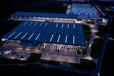 Gece vakti malzeme deposunun havadan görüntüsü. Sanayi bölgesindeki lojistik merkezi yukarıdan. Lojistik merkezde yüklenen kamyonların hava görüntüsü. İnsansız hava aracından görüntüle.