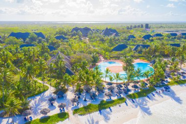 Güneşli bir günde tropikal kumsal manzarası, palmiyeler ve şemsiyelerle. Hint Okyanusu 'nda yaz tatili, Zanzibar, Afrika. Palmiye ağaçları, oteller, havuz, beyaz kum, gök mavisi deniz manzarası. Üst görünüm