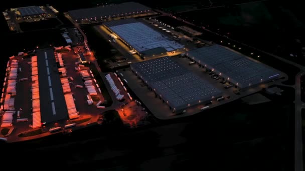 Aerial view of the large logistics park with warehouse, loading hub with many semi-trailers trucks standing at the ramps for load/unload goods at night. — Stock Video