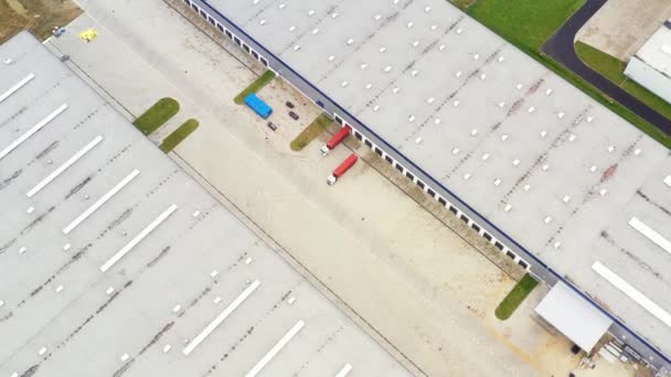 Vista aerea del magazzino merci. Centro logistico nella zona industriale della città dall'alto. Vista aerea di camion che caricano presso il centro logistico. Vista dal drone. — Video Stock