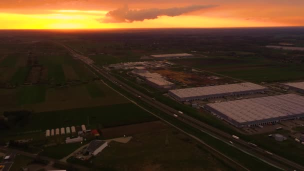 Luftaufnahme des Logistikparks mit Lager, Verladebahnhof und vielen Sattelschleppern mit Ladeanhängern, die bei Sonnenuntergang an den Rampen zum Be- und Entladen von Waren stehen — Stockvideo