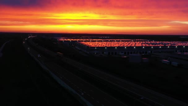 Vue panoramique aérienne du parc logistique avec entrepôt, moyeu de chargement avec de nombreux semi-camions avec remorques de fret debout sur les rampes pour le chargement / déchargement des marchandises au coucher du soleil — Video