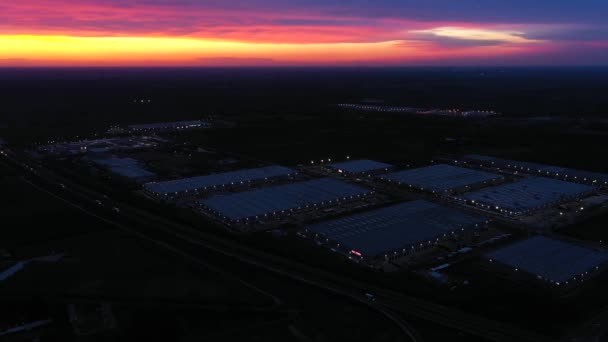 Panoramiczny widok z lotu ptaka na park logistyczny z magazynem, centrum załadunku z wieloma naczepami z przyczepami towarowymi stojącymi przy rampach do załadunku / rozładunku towarów o zachodzie słońca — Wideo stockowe