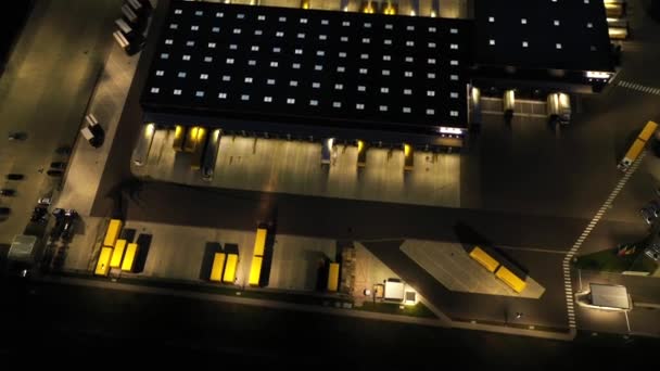 Luftaufnahme eines Logistikparks mit Verladebahnhof. Sattelschlepper stehen nachts an Lagerrampen zum Be- und Entladen von Waren. — Stockvideo