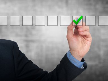Businessman ticks off in in a square. Task list concept. Isolated on grey background.