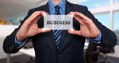 Businessman holds white card with Business sign. Isolated on various backgrounds ( grey, blue, office, white) - Stock Image