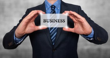Businessman holds white card with Business sign. Isolated on various backgrounds ( grey, blue, office, white) - Stock Image
