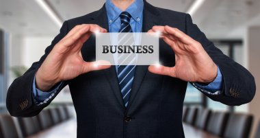 Businessman holds white card with Business sign. Isolated on various backgrounds ( grey, blue, office, white) - Stock Image