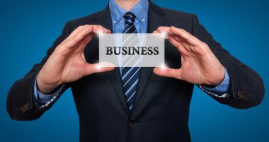 Businessman holds white card with Business sign. Isolated on various backgrounds ( grey, blue, office, white) - Stock Image